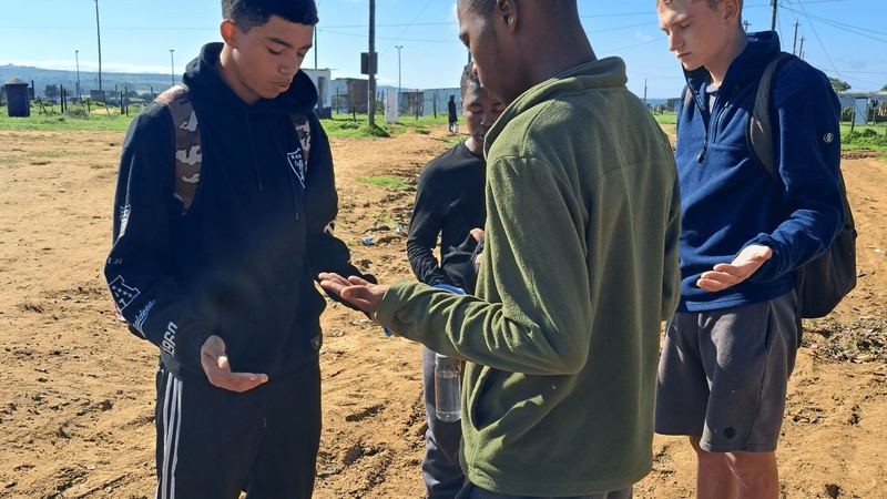 Young team members praying with a man in Port Alfred
