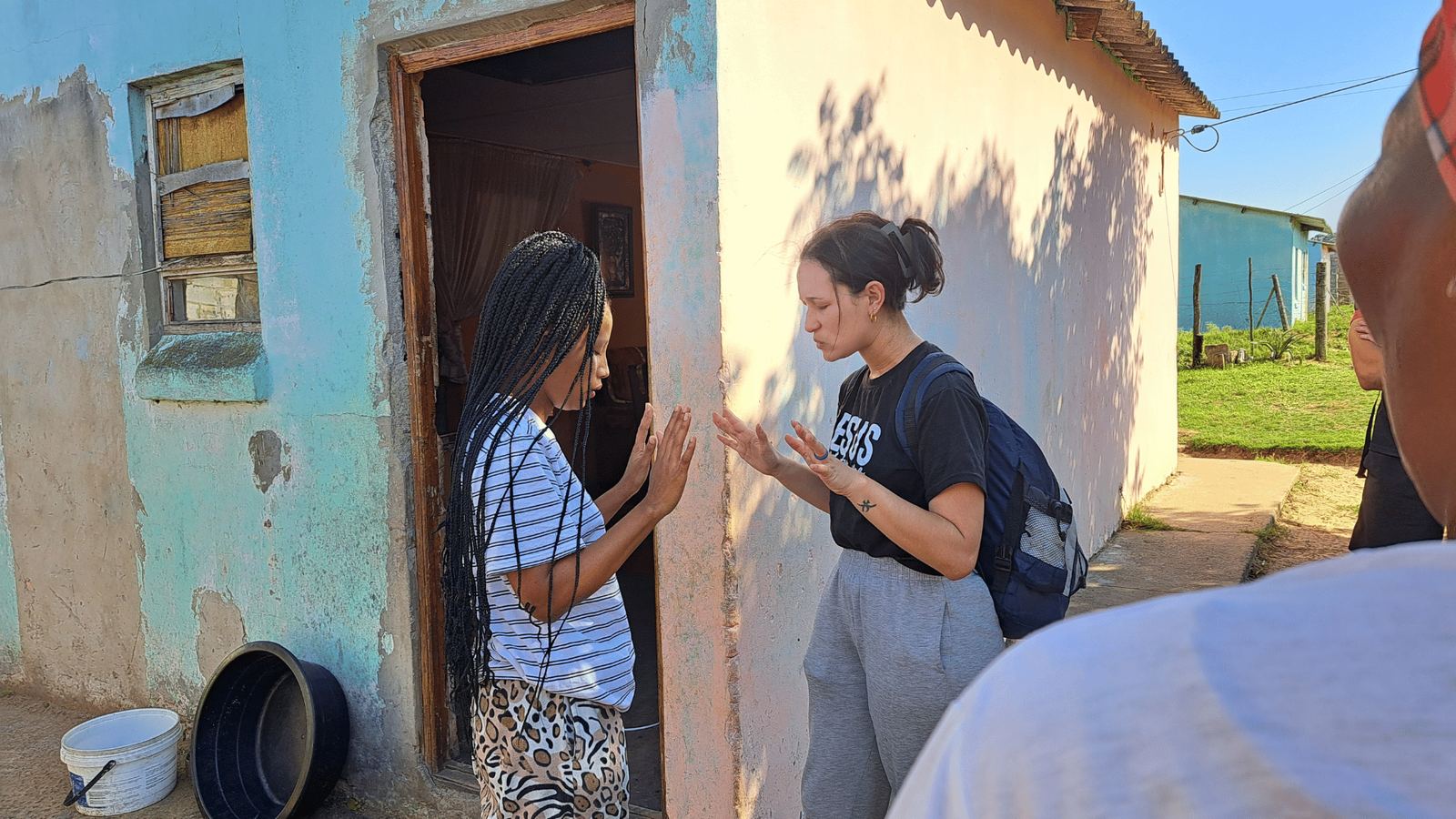 Faith Missions team member praying with a young woman at her front door
