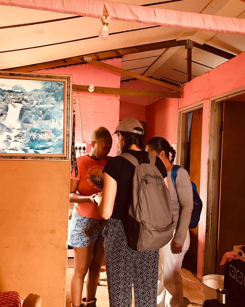 Team members praying with a young woman inside her home