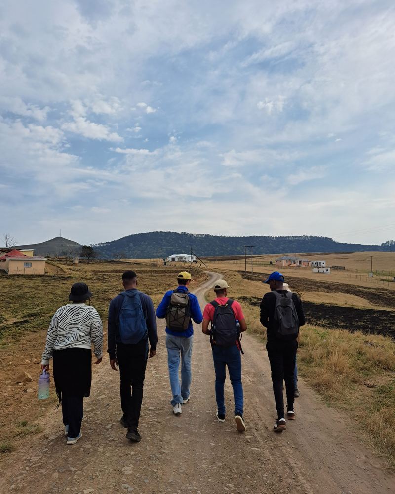 Mission team with backpacks walking down a rural dirt road