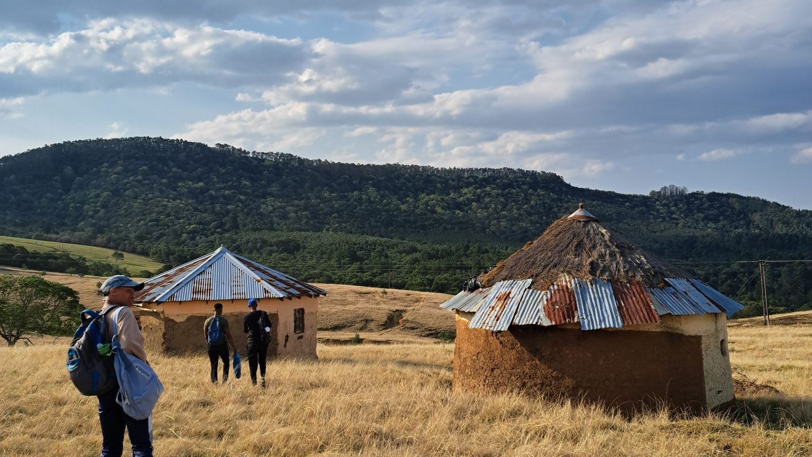 Mission team walking through golden grassland towards village huts